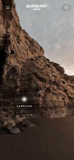 Screenshot from a 360 video campaign for Burberry. It shows a rock formation on a beach, with a button and text reading'campaign'.