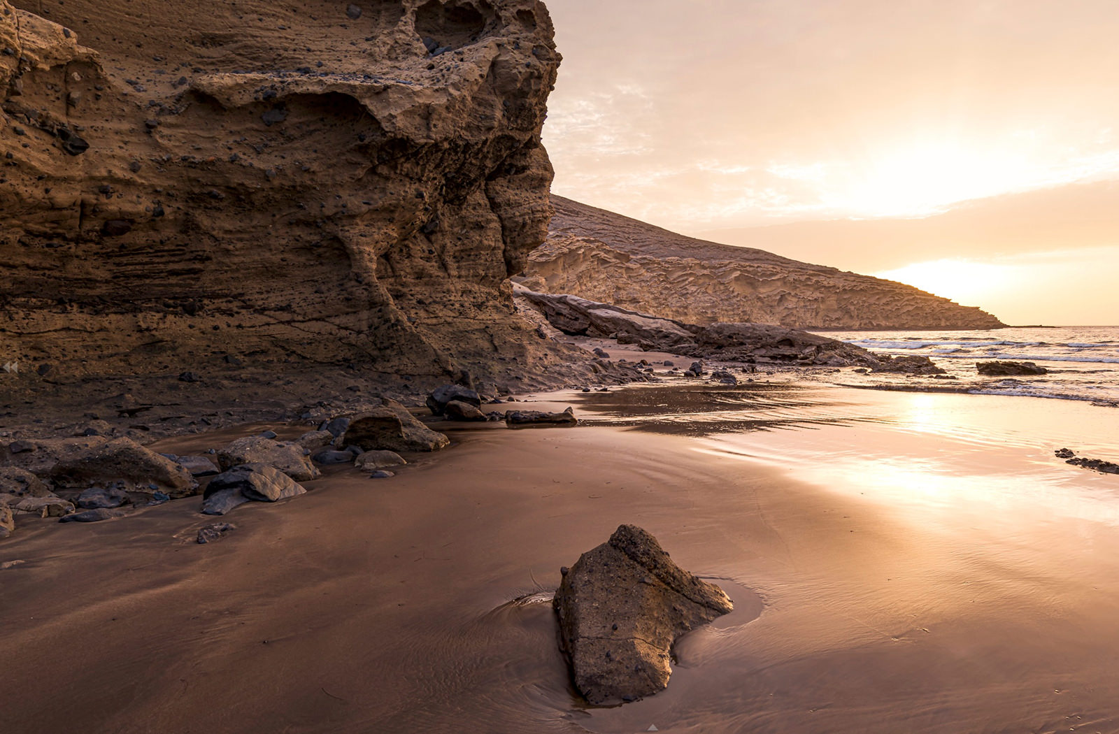 Still taken from a 360 video shot for the Burberry Hero campaign. Moody image of a beach in Tenerife at sunset, looking over volcanic rock and black sand towards the sea.